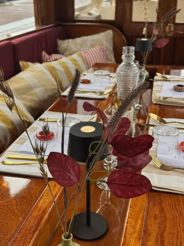 Table set for dinner with a candle lamp and cushions in a wooden canal boat cabin