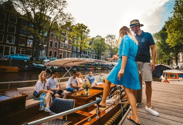 Guests step aboard Pure Spirit from a wooden dock while others sit in the lounge