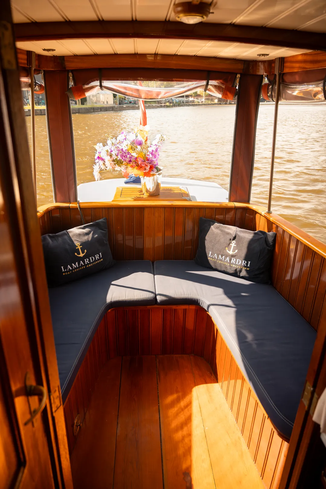 Navy cushioned seating at the stern of the salon boat with LAMARDRI pillows and fresh flowers