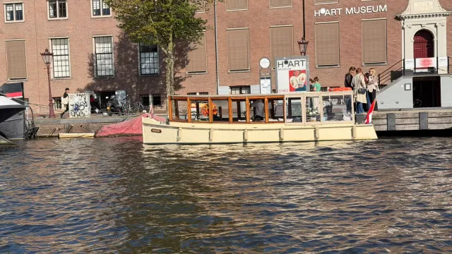 Cream salon boat Energie moored in front of the H'ART Museum on the Amstel in Amsterdam