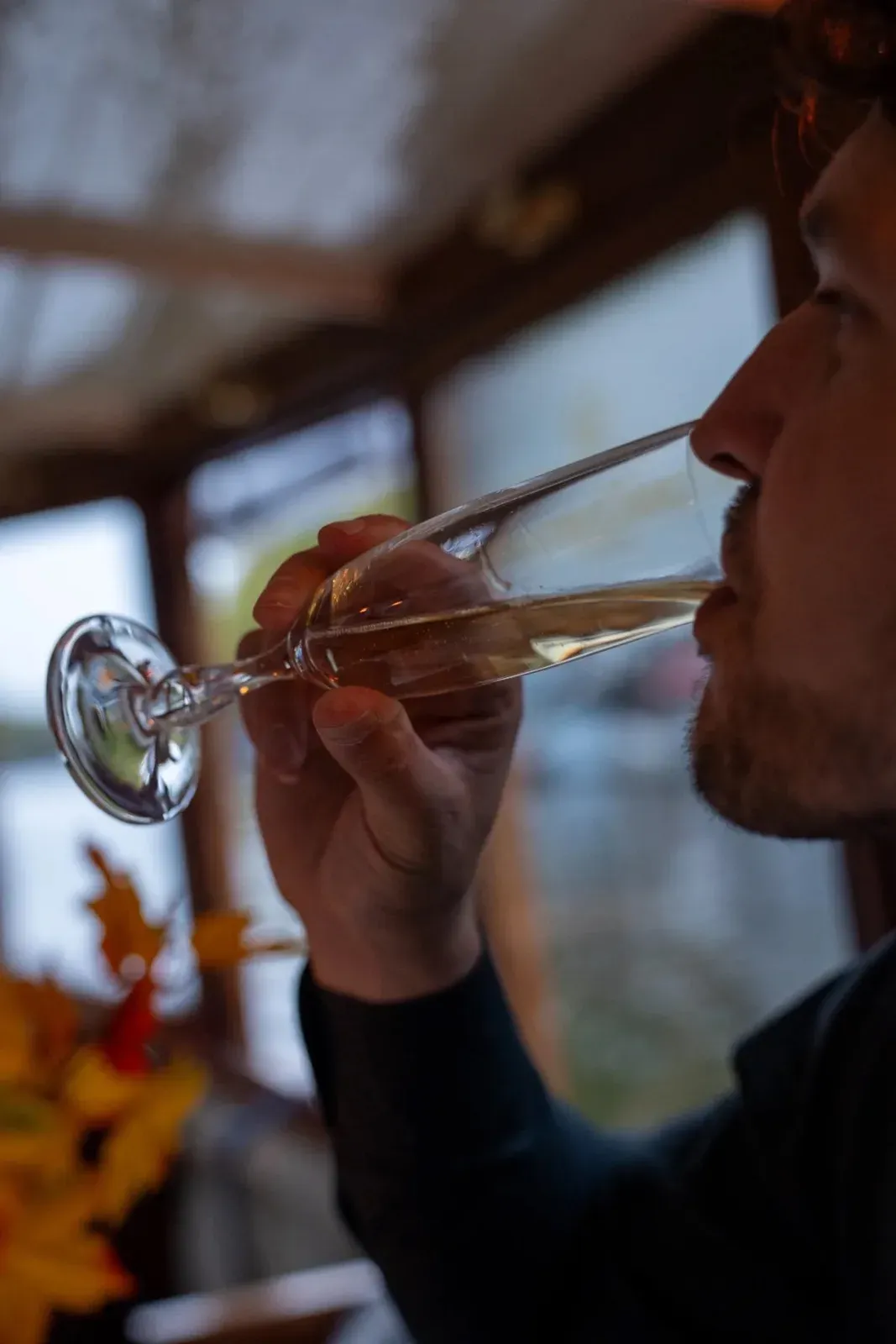 Guest sips a glass of wine inside the salon of the boat, with autumn flowers on the table