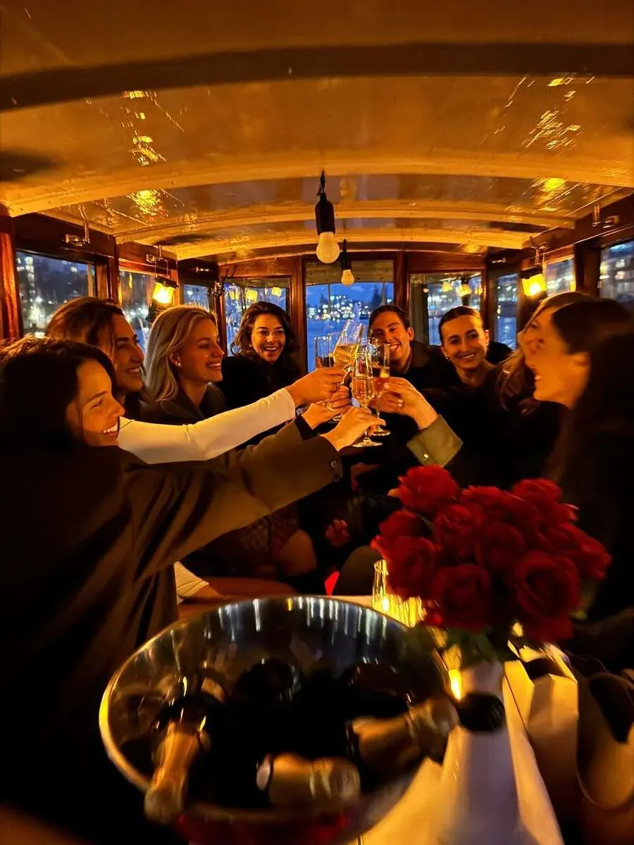 Guests raise glasses in a toast inside the warm wooden salon of Energie, with red roses on the table