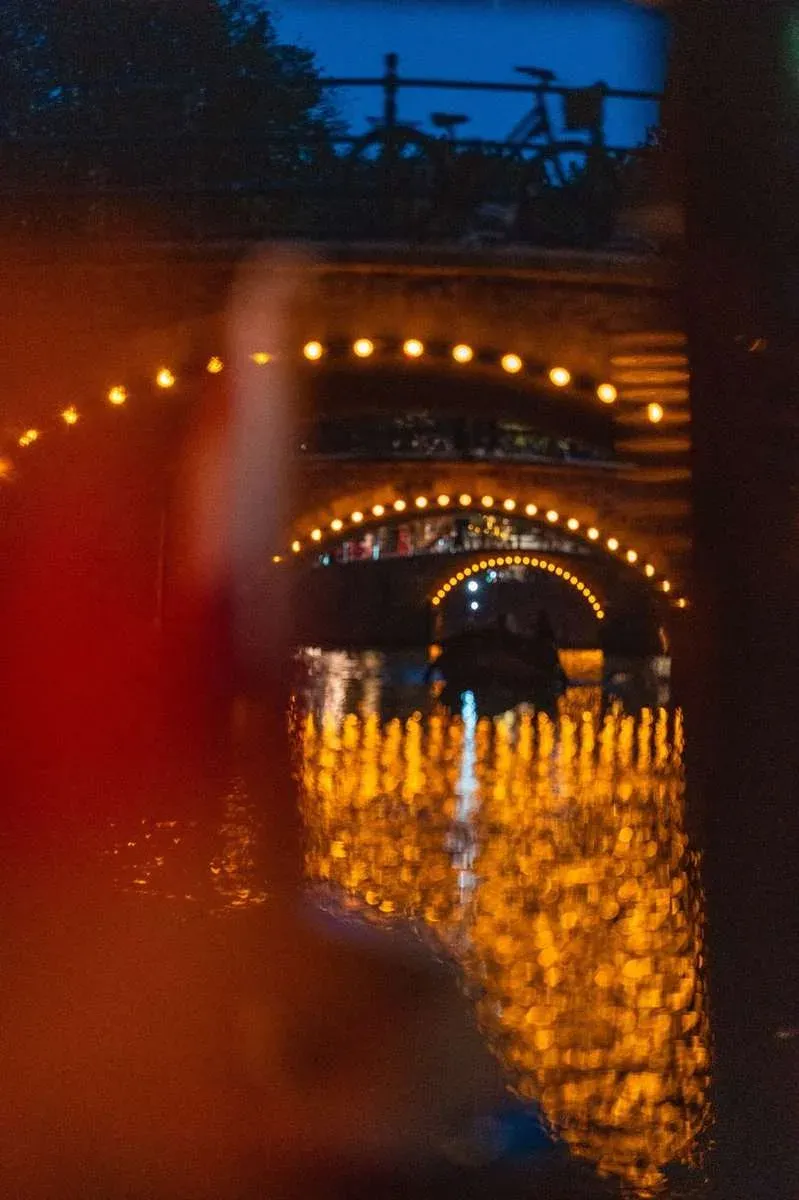 Bridges outlined in glowing lights seen through the window of a boat on an Amsterdam canal