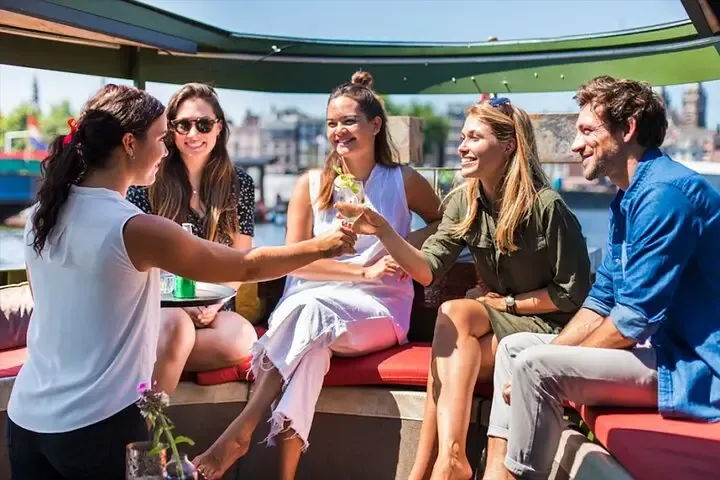 Passengers relaxing with drinks aboard an Amsterdam canal cruise boat